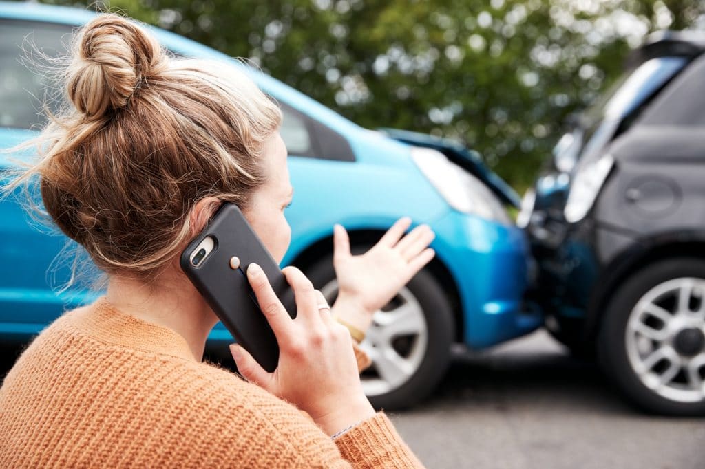 Automobilista femminile coinvolto nell'incidente d'auto che chiama compagnia di assicurazioni o servizio di recupero
